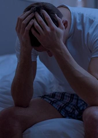 Man sitting on the edge of the bed feeling low on energy